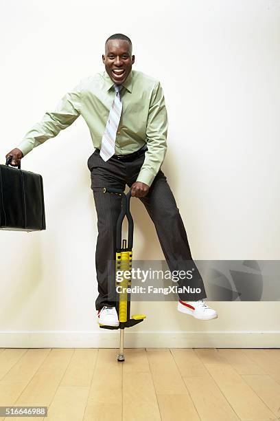 businessman on a pogo stick - pogo stick stock pictures, royalty-free photos & images