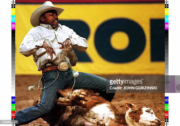 Fred Whitfield releases the ties and throws his arms into the air to signal that the calf is roped during the Calf Roping event at the National...