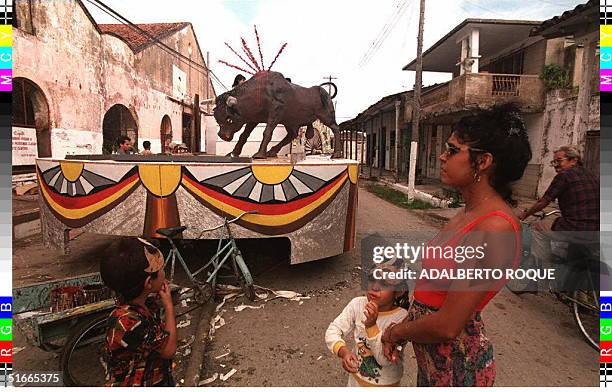Amother and her two children watch the construction of a float depicting bullfighting 28 December in Remedios, Cuba, some 350 kms east of Havana,...