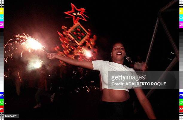 Young Cuban woman dances while waving fireworks during the annual parade to bring in the New Year 29 December in Remedios, some 350 kms east of...
