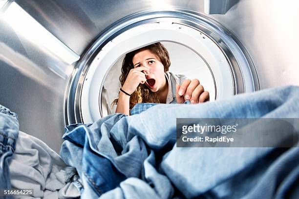 blanchisserie à gauche dans sèche-linge sent mauvais ! satisfait femme détient le nez. - moisissure photos et images de collection