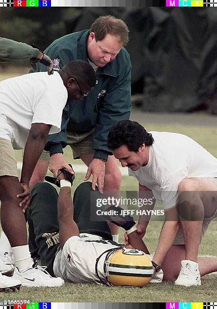 Green Bay Packers head coach Mike Holmgren stands over injured player Derrick Mayes as trainers work on him during their practice 22 January in New...