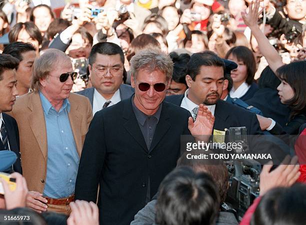 Surrounded by fans and body guards, US movie star Harrison Ford waves to the crowds as he arrives at a main theatre to attend the opening ceremony of...