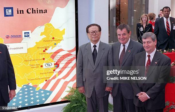 Chinese President Jiang Zemin poses in front of a map showing US company General Motors presence in China with GM Chairman Jack Smith and his brother...