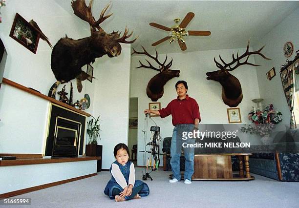 By Karen Lowe Pao Moua and his daughter Khayee, three, pose for the photographer in the family living room where record elk trophies and a moosehead...