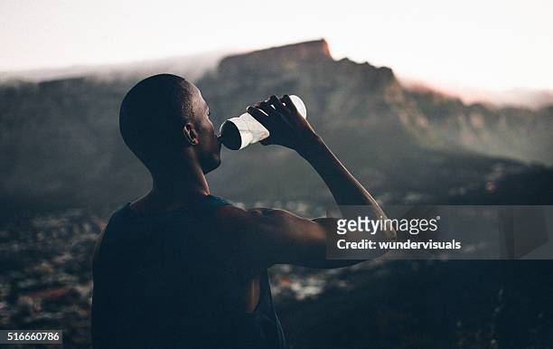 african decent athlete drinking water after a fitness achievemen - running refreshment stock pictures, royalty-free photos & images
