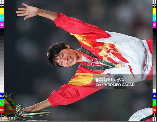 Wang Junxia from China celebrates on the podium during the medal ceremony after winning the gold medal in the women's Olympic 5,000m event at the...