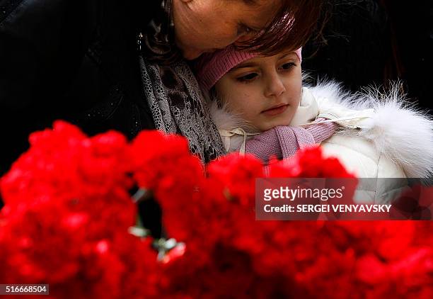 Woman and child pay a tribute to victims of an air-crash at the Rostov-on-Don airport entrance on March 20, 2016. A flydubai passenger Boeing jet...