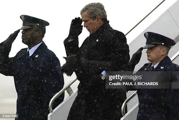 President George W. Bush carries his dog Barney as he salutes Air Force personnel on the steps of Air Force One after landing in the snow at Andrews...