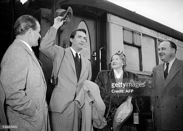 Actor Gregory Peck waves to wellwishers 07 April 1950 at a Paris' railway station upon his arrival to Paris as his wife watches. Vetaran US film star...