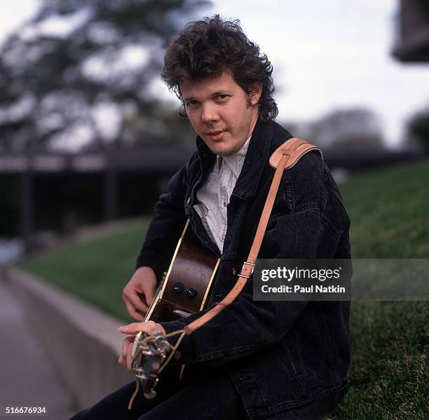 Portrait of American Folk and Pop musician Steve Forbert as he poses, with his guitar, outside the Park West Auditorium, Chicago, Illinois, October...