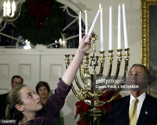 President George W. Bush watches as Daniella Wald of New York City, raises a lights a menorah on the 6th night of Hanukkah 04 December 2002 during...