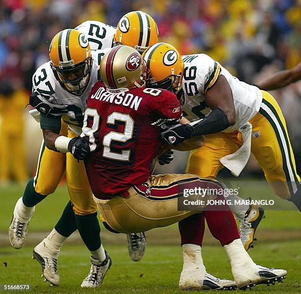 San Francisco 49ers' tight-end Eric Johnson is stopped by Green Bay Packers' cornerback Tyrone Williams , Packers' linebacker Hardy Nickeerson , and...