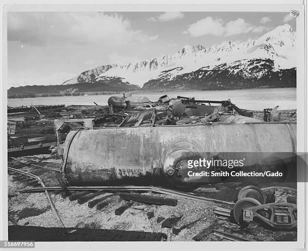 Photograph that shows a view of the Alaska Railroad yard in Seward as it appeared after the 1964 Alaska earthquake, the railroad tracks, train cars,...