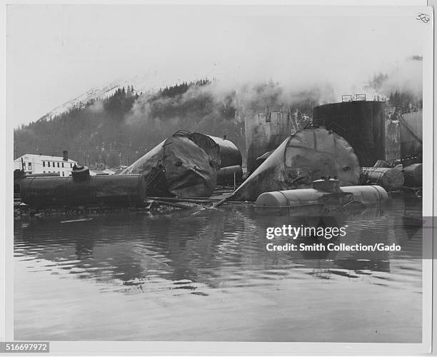 Photograph of the damage done to the Alaska Railroad Yard and Texaco bulk plant after the 1964 Alaska earthquake, large tanks and rail cars can be...