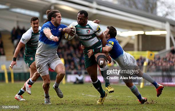 Vereniki Goneva of Leicester Tigers is tackled by Mike Ellery and Neil de Kock of Saracens during the Aviva Premiership match between Leicester...