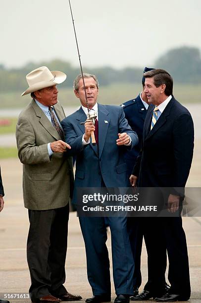 President George W. Bush is given a fishing pole by Ray Scott as Alabama's gubernatorial candidate Bob Reilly watches at the airport 24 October 2002...