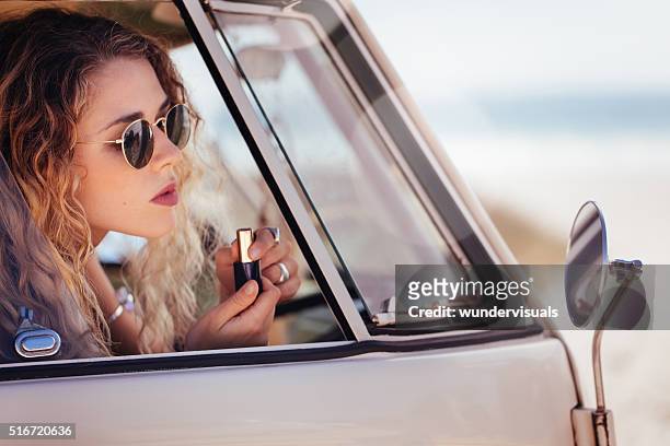 hipster mädchen setzen auf lippenstift in spiegel der van sideview - us girls on the beach stock-fotos und bilder