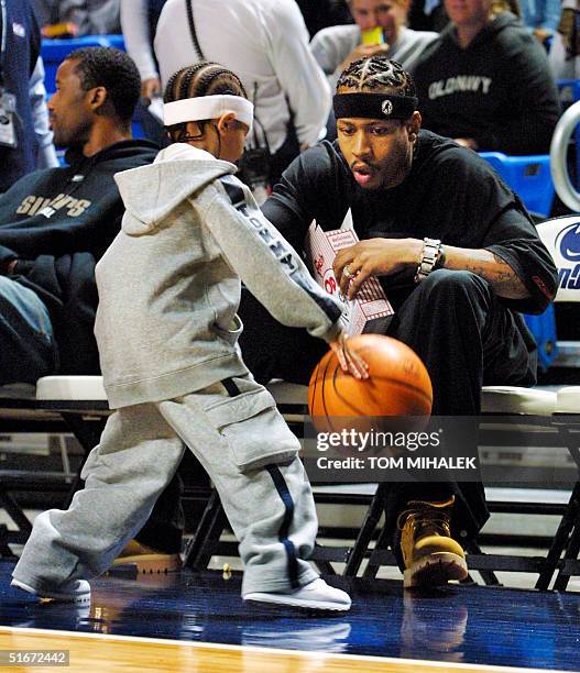 Allen Iverson of the Philadelphia 76ers watches as his son Allen "Deuce" Iverson bounces a basketball near the team's bench prior to the start of a...