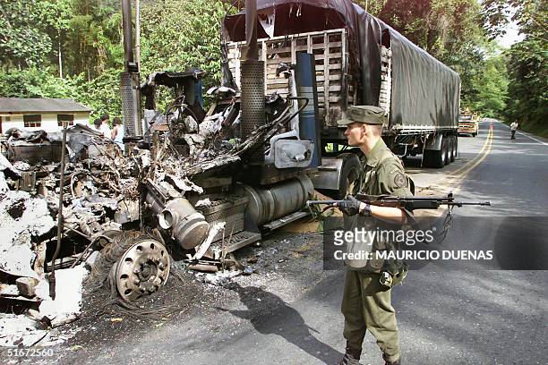Colombian government soldier walk past one of the four trucks that were set afire by guerrillas of the Revolutionary Armed Forces of Colombia 10...