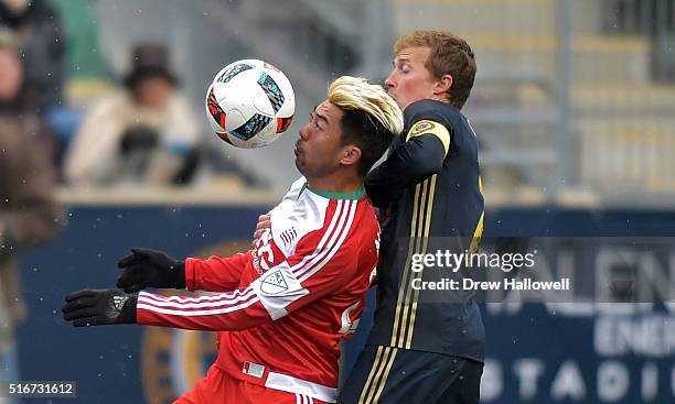 Lee Nguyen of New England Revolution plays the ball while holding off Brian Carroll of Philadelphia Union at Talen Energy Stadium on March 20, 2016...