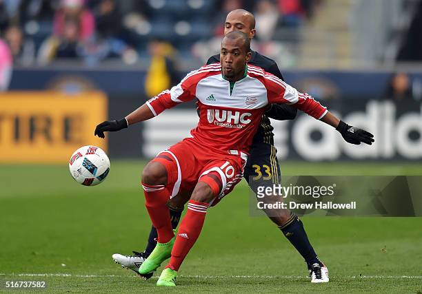 Teal Bunbury of New England Revolution plays the ball while holding off Fabinho of Philadelphia Union at Talen Energy Stadium on March 20, 2016 in...