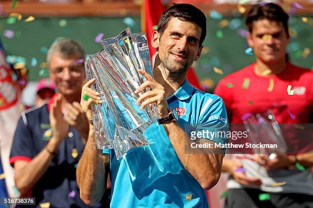 Novak Djokovic of Serbia celebrates with the winner's trophy after defeating Milos Raonic of Canada during the mens final of the BNP Paribas Open at...