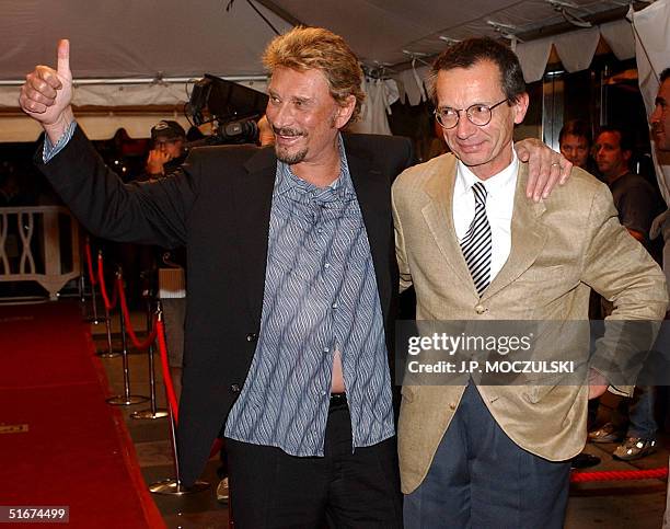 The French "Elvis", film star Johnny Hallyday , gives the thumbs up to screaming fans while arriving with director Patrice Leconte for the North...