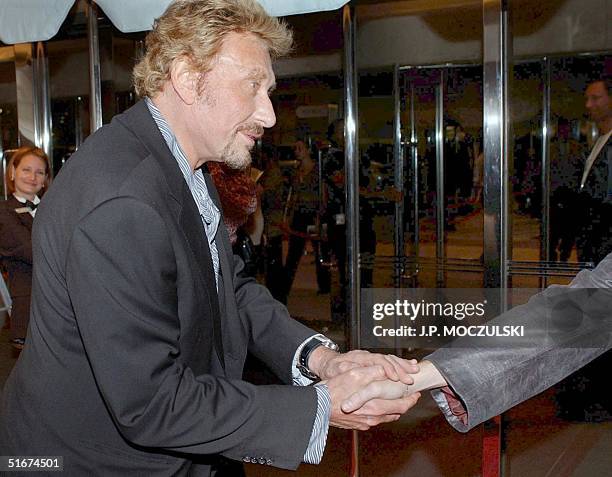 The "French Elvis", film star Johnny Hallyday, stops to shake a fans hand while arriving for the North American Premiere screening of his new film...