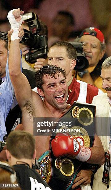 Oscar de la Hoya of the United States holds his belts as he celebrates his 11th round TKO victory over compatriot Fernando Vargas 14 September 2002...