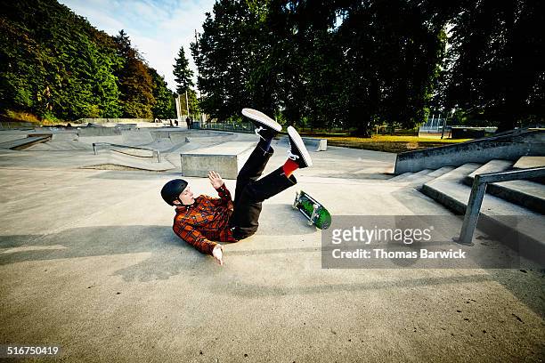 skateboarder falling off of railing in skate park - skate stock-fotos und bilder