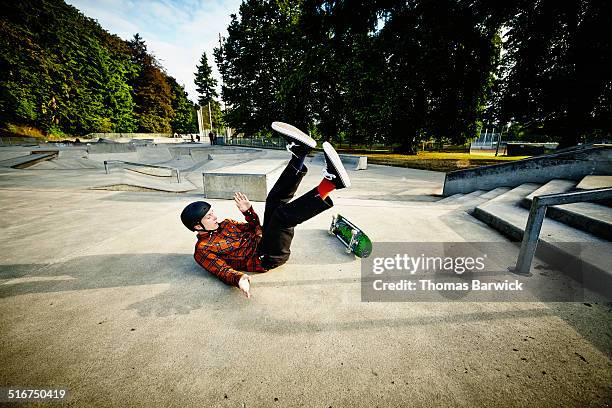 skateboarder falling off of railing in skate park - skateboard stock pictures, royalty-free photos & images