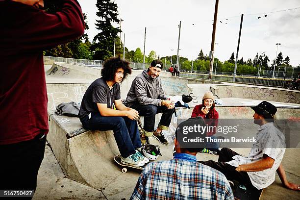 skateboarders sitting in discussion in skate park - boy skatepark stock-fotos und bilder