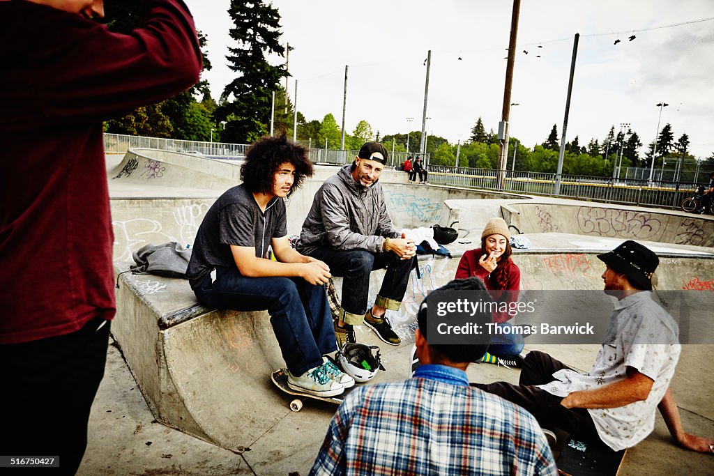 Skateboarders sitting in discussion in skate park