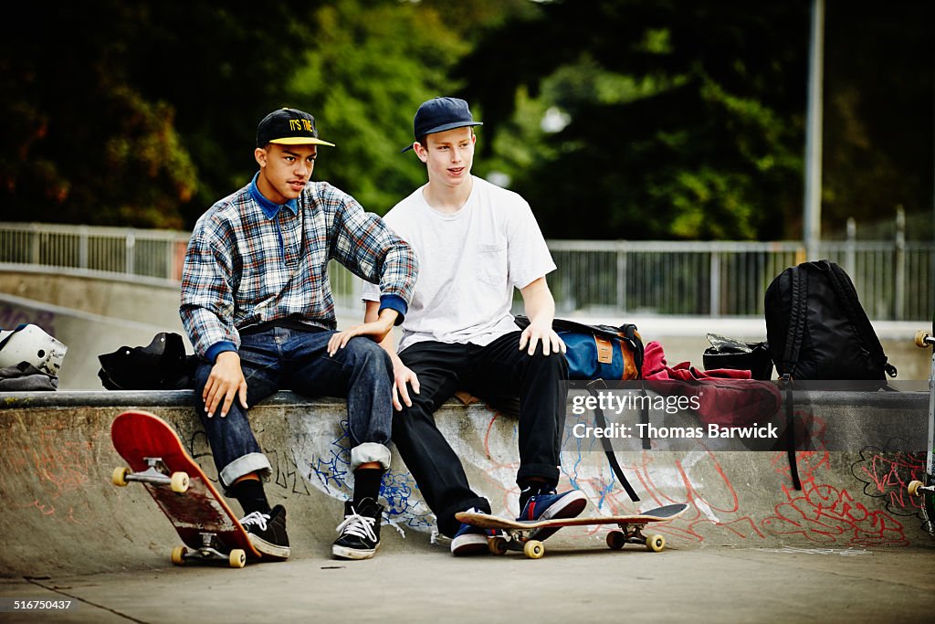 Two male skaters watching friends skate in park