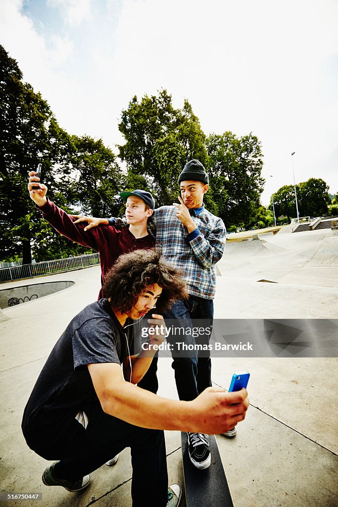 Skateboarders taking self portraits in skate park