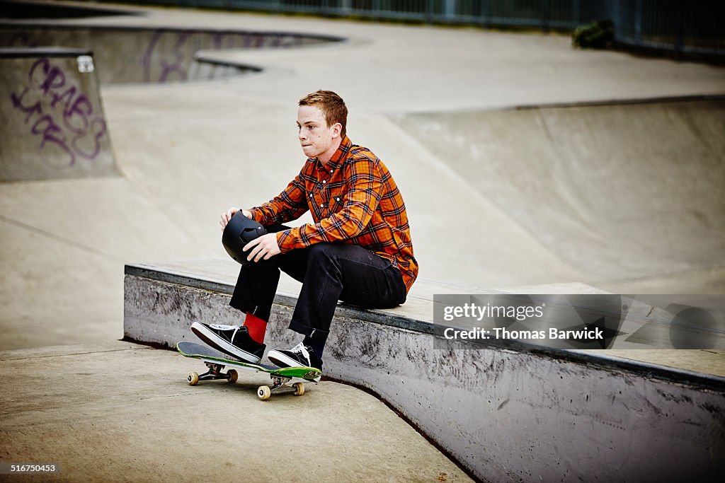 Male skater sitting in skate park holding helmet