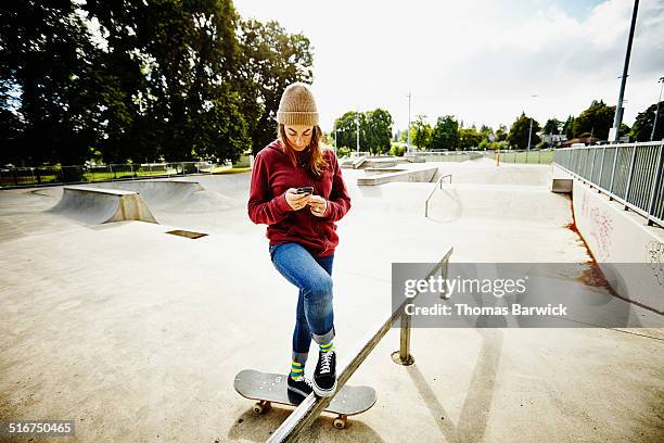 skateboarder looking at smartphone in skate park - skateboard park imagens e fotografias de stock