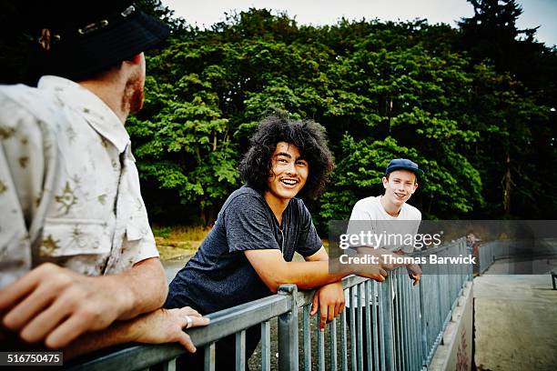 skateboarders leaning on fence around skate park - skateboard park imagens e fotografias de stock