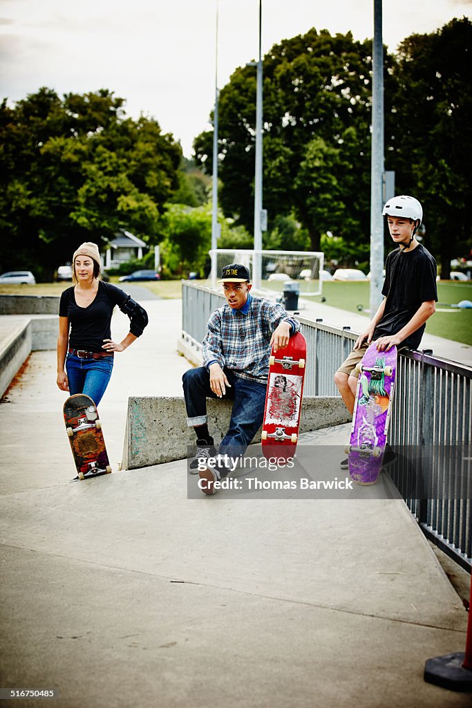 Skateboarders watching friends ride in skate park