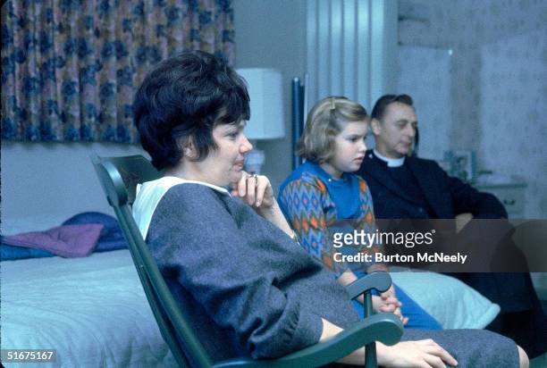 Marilyn Lovell, wife of Gemini 7 astronaut Jim Lovell, sits in a rocking chair in a bedroom with her yougest daughter Susan and her pastor, Father...
