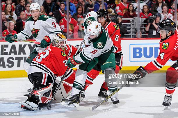 Goalie Scott Darling of the Chicago Blackhawks stops the shot from Zach Parise of the Minnesota Wild, as Niklas Hjalmarsson reaches across and...