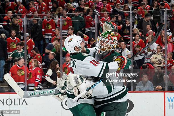 Jason Zucker and goalie Devan Dubnyk of the Minnesota Wild celebrate after defeating the Chicago Blackhawks 3 to 2 in a shoot-out during the NHL game...