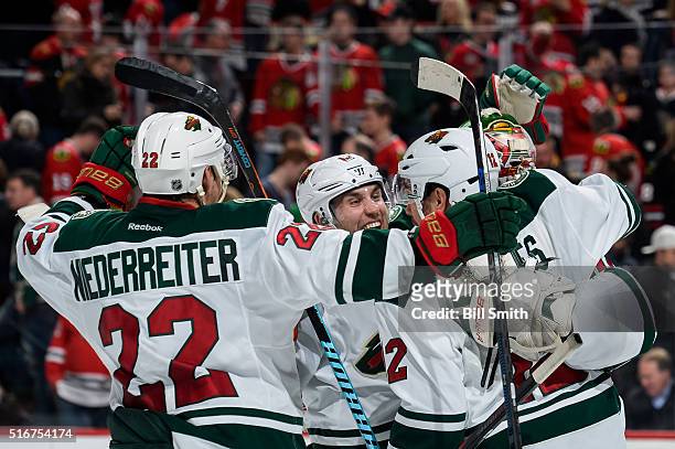 Jason Zucker of the Minnesota Wild celebrates with teammates after defeating the Chicago Blackhawks 3 to 2 in a shoot-out during the NHL game at the...