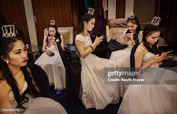 Debutantes from a local academy look at their mobile phones before taking part in the Vienna Ball at the Kempinski Hotel on March 19, 2016 in...