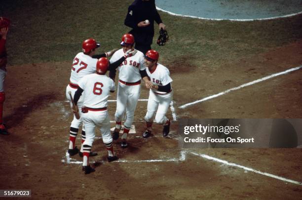 Fred Lynn of the Boston Red Sox crosses home plate after hitting a first inning home run as teammates Carl Yastrzemski, Carlton Fisk, and on-deck...