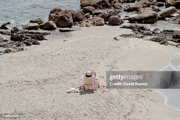 Woman reads a book as she sunbathes on the beach on March 17, 2016 in Benalmadena, Spain. Spain is Europe's top destination for British expats with...