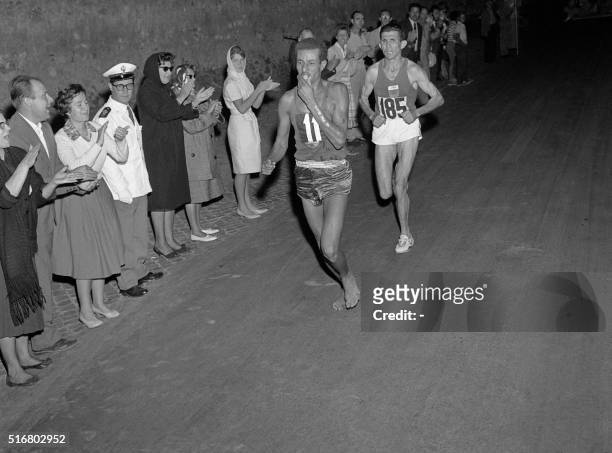 Ethiopian athlete Abebe Bikila runs barefoot for victory in the Rome 1960 Olympic Games marathon, after passing Moroccan Abdeslam Radi, on September...