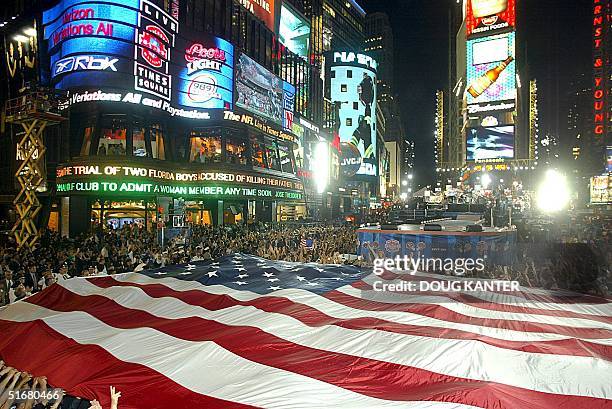 Police hold up a giant American flag at the conclusion during the NFL 2002 season kickoff concert in Times Square in New York 05 September 2002. AFP...