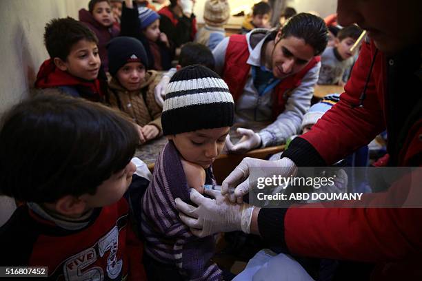 Members of the DOuma branch of the Syrian Arab Red Crescent administer vaccinations to children at a school in the rebel-held city of Douma,...